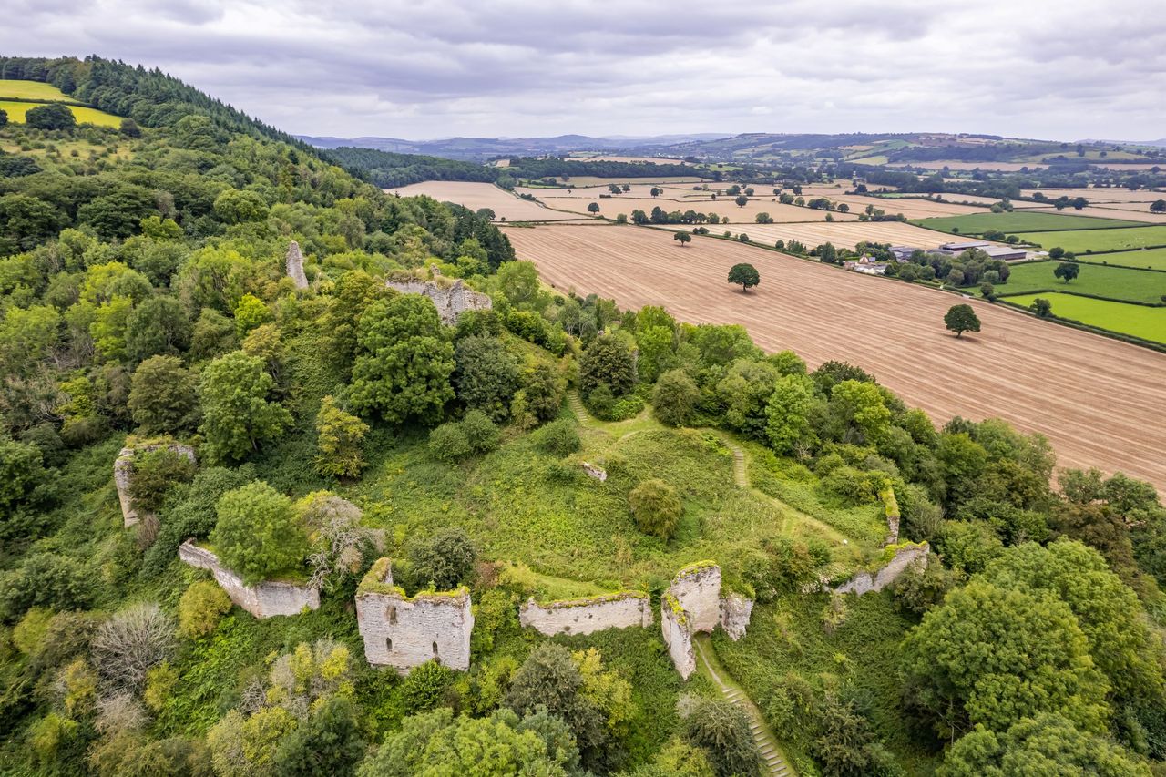 Old ruins on a hillside next to a large field used for jousting