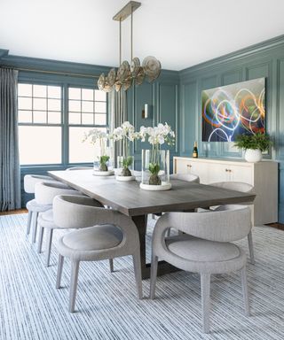 Dining room with table and upholstered chairs, sideboard and gray paneled walls