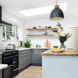 Open plan kitchen with grey cabinets, white worktops, and blue kitchen island