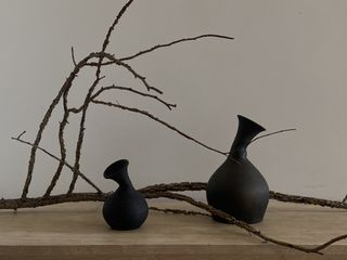 Black vases next to tree branch