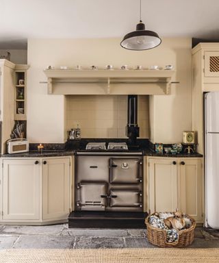 A character kitchen has cream colored walls and cream cabinetry with a black aga cooker in the middle