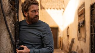 Tom Harris (Gerard Butler) looks around a corner in a scene from "Kandahar" (2023)