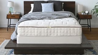 A Naturepedic mattress atop a black bedframe in a gray bedroom