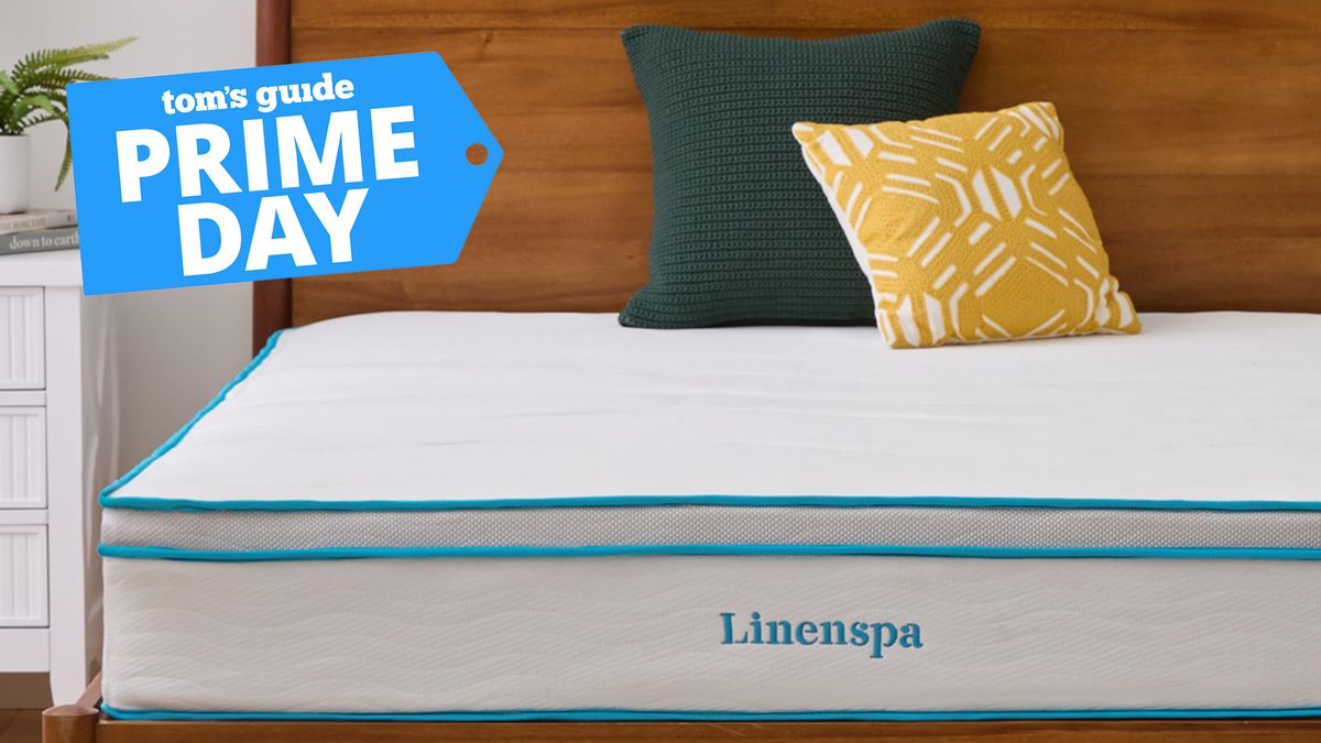 A close up of the Linenspa 10&quot; Memory foam and Spring Hybrid mattress on a wooden bed frame, with two cushions resting against the headboard. A Tom&#039;s Guide Prime Day deals&#039; graphic (left)