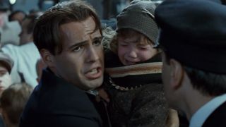 Cal looking scared while holding a child in Titanic