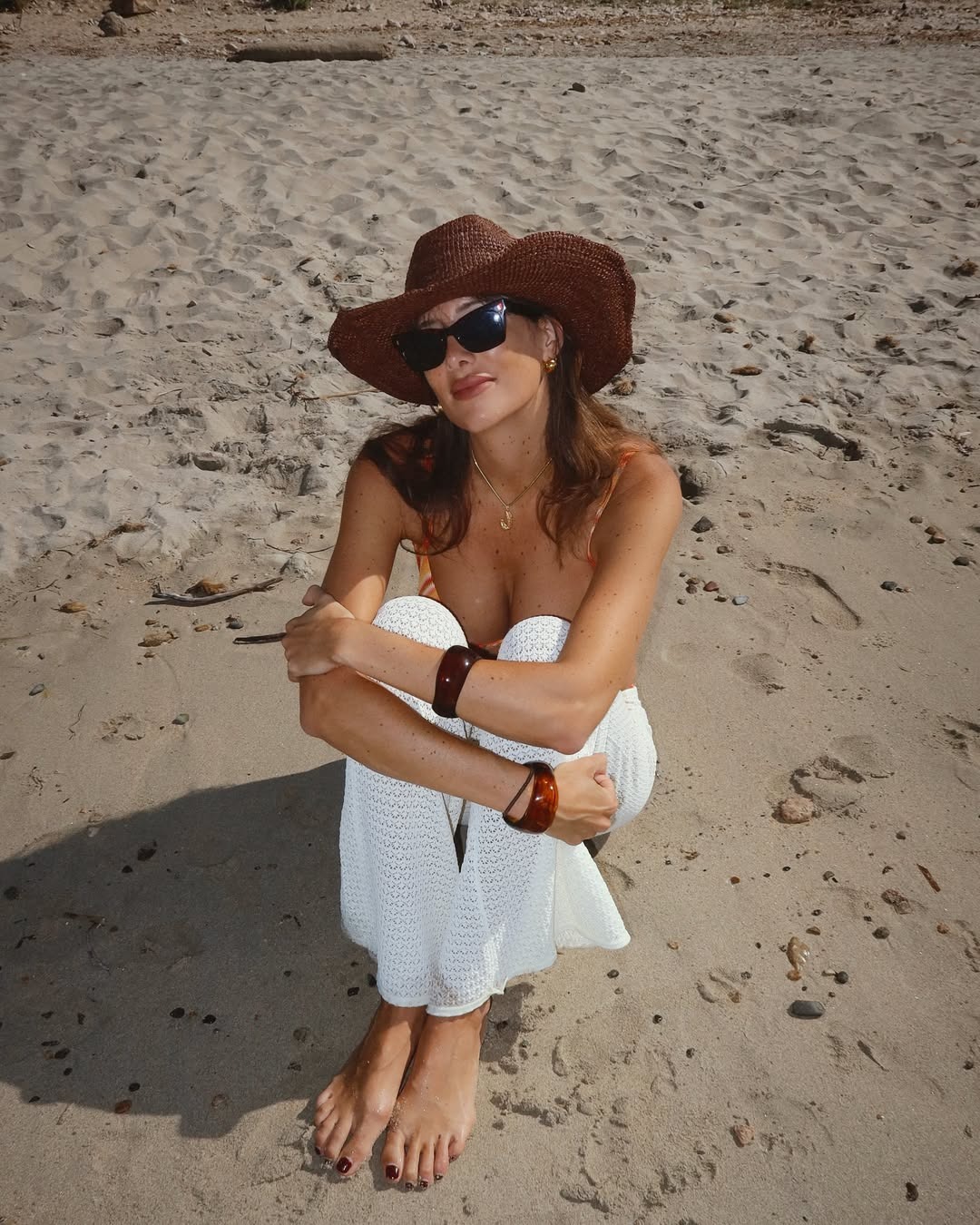 Creator @juliesfi sitting on the beach with a chocolate brown pedicure