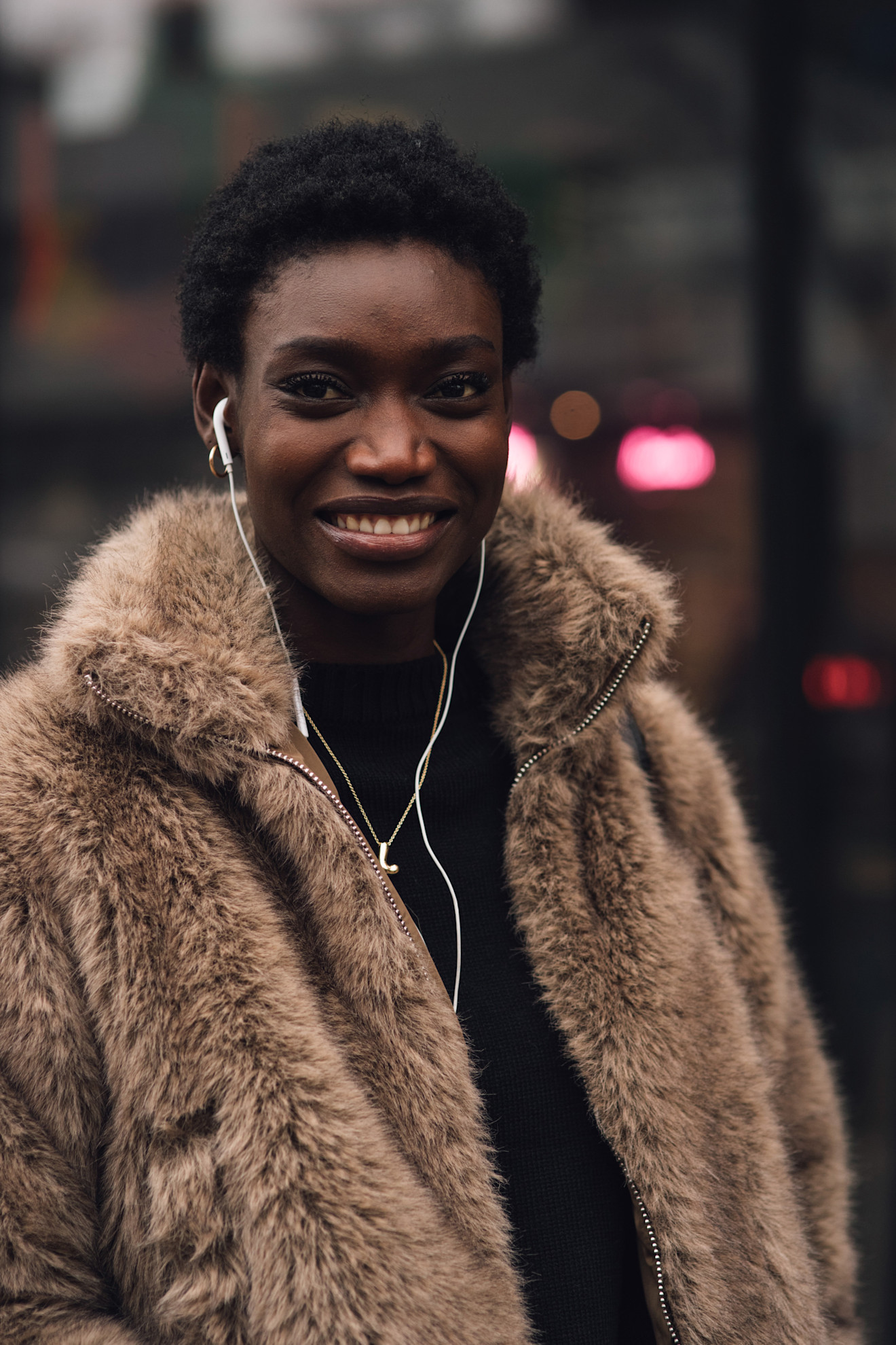 a woman in a shearling jacket with a teeny weeny afro and white headphones