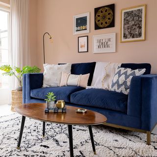 pink living room with blue velvet sofa and berber rug