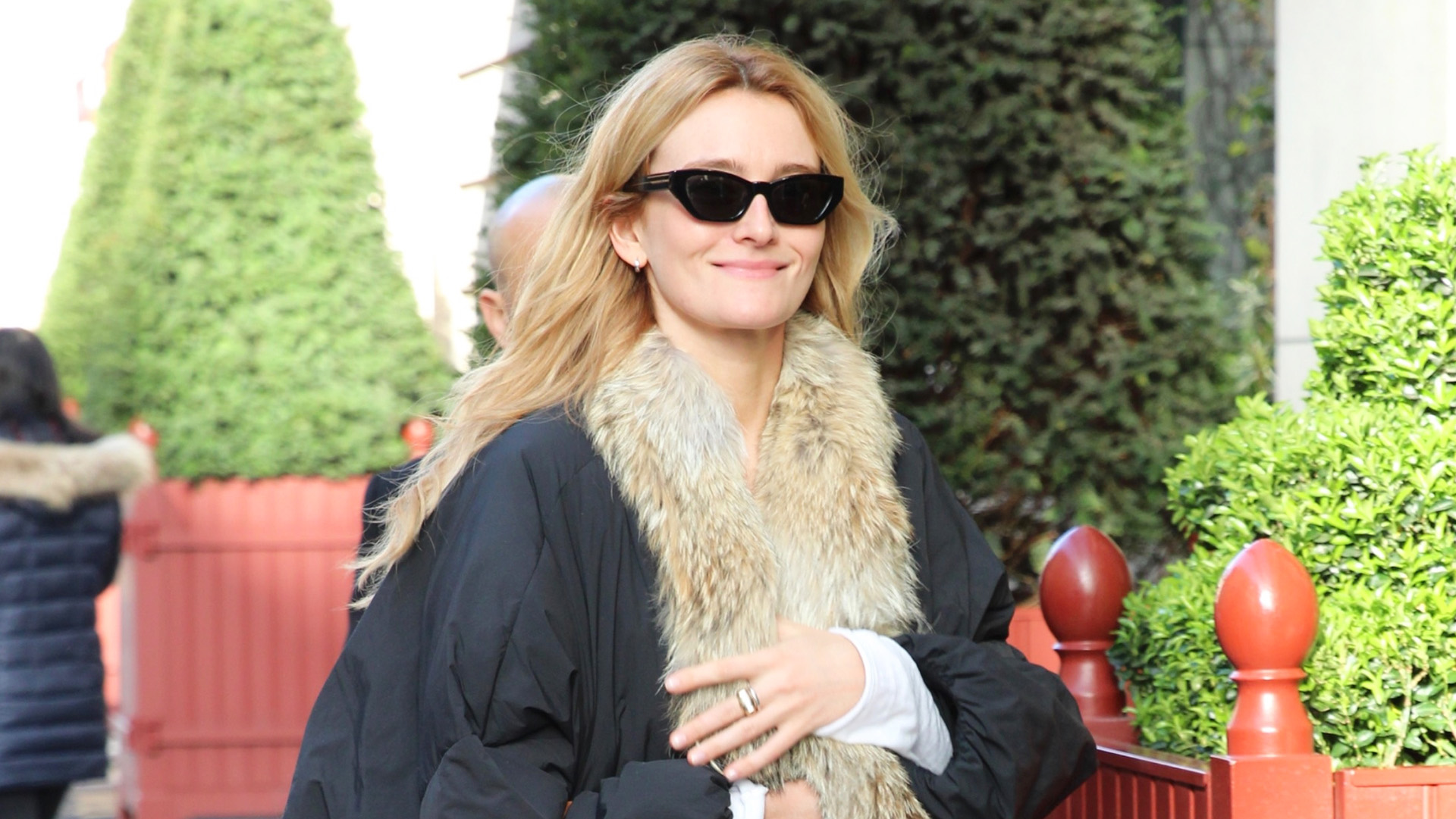 Sarah Pidgeon wearing a fur-trimmed black coat, light-wash jeans, a cognac Balenciaga Rodeo Bag, and black ankle boots.