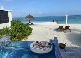 Breakfast served on a pool on a floating tray overlooking a beach and turquoise blue sea in the Maldives