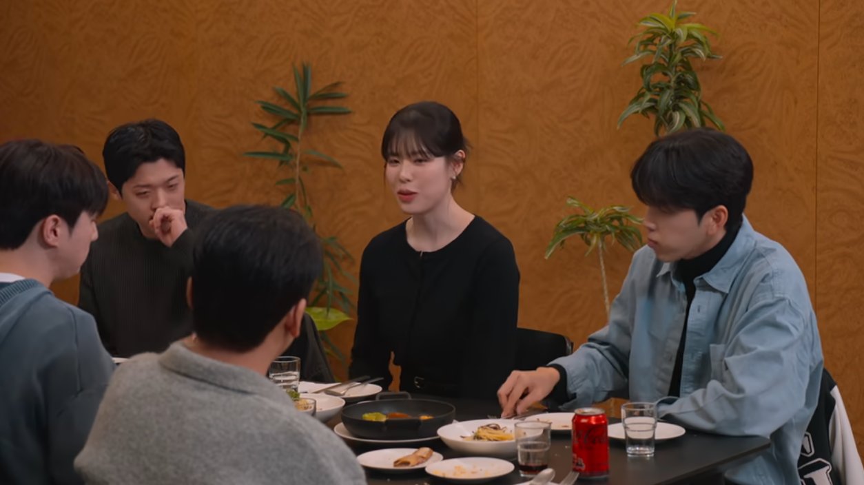 Female contestant An Jeong-eun sits with the male contestants at a dinner table on Netflix's 'Better Late Than Single' season 2.