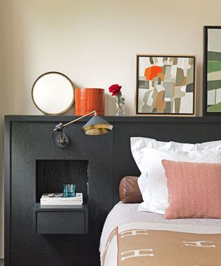 bedroom with black panelling, artwork, bed and pillows