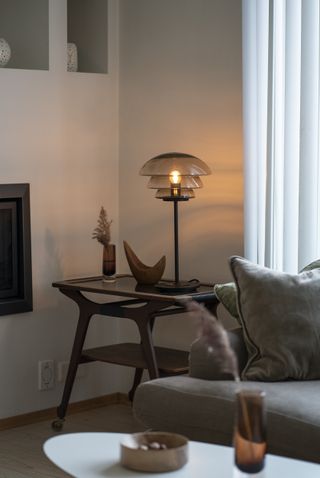 living room with retro side table with retro glass tired lamp, velvet couch, oval side table, alcoves