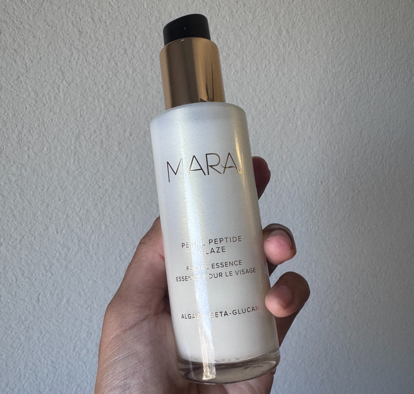 Hand holding a bottle of Mara's Pearl Peptide Glaze.