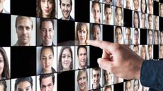 A man points at a woman's photo among many on a digital display.
