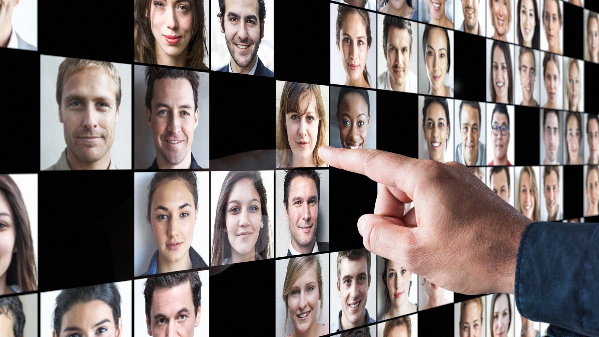A man points at a woman's photo among many on a digital display.