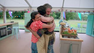 Three contestants hug in the tent after finishing their bakes, on 'The Great British Baking Show.'