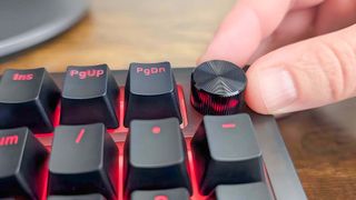 A forefinger and thumb rotating the volume dial on the iBuyPower MK9 Pro RGB Mechanical Keyboard.