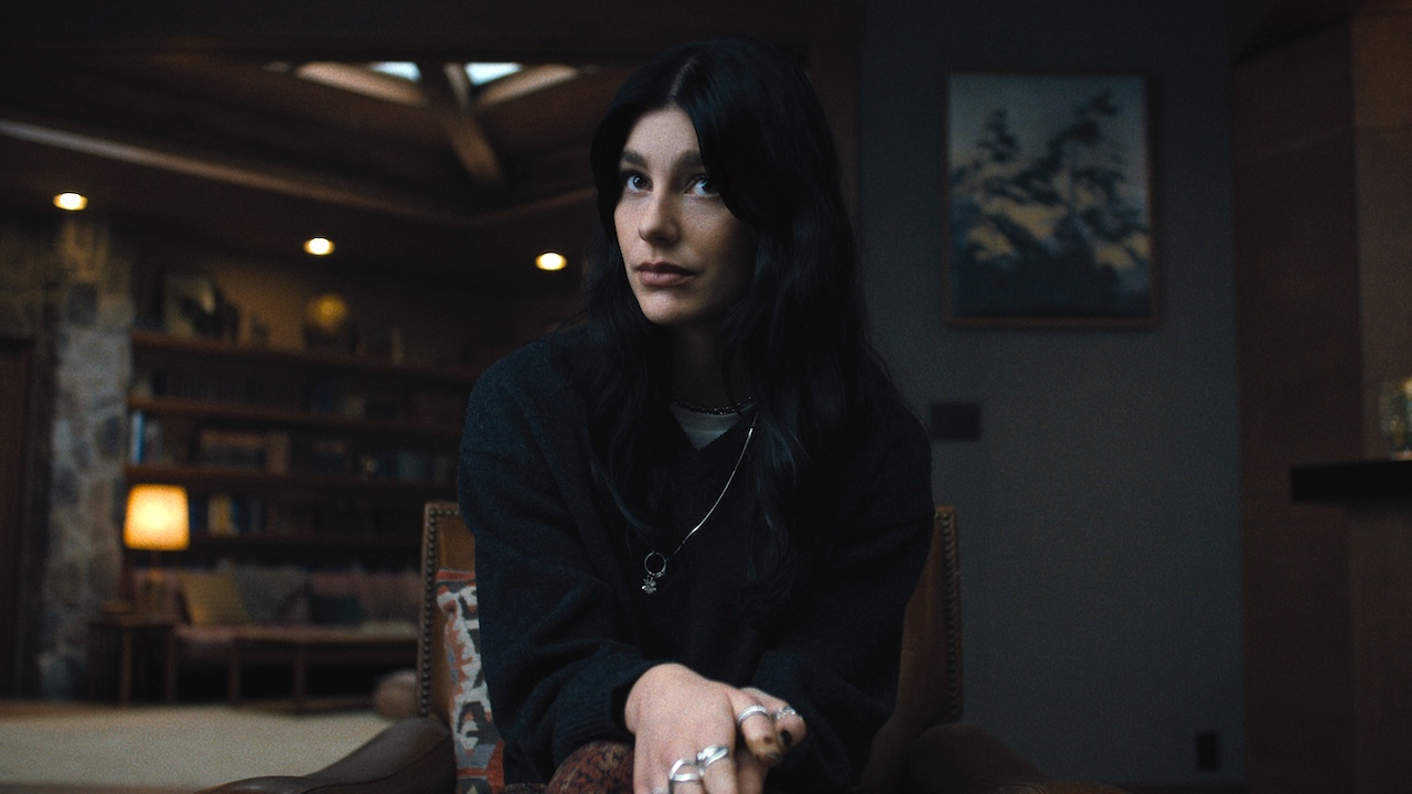 Rachel wearing black shirt sitting in living room in Something Very Bad Is Going To Happen