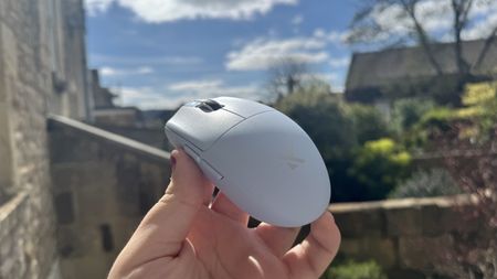 The blue Mchose G3 V2 gaming mouse held in a hand, outside