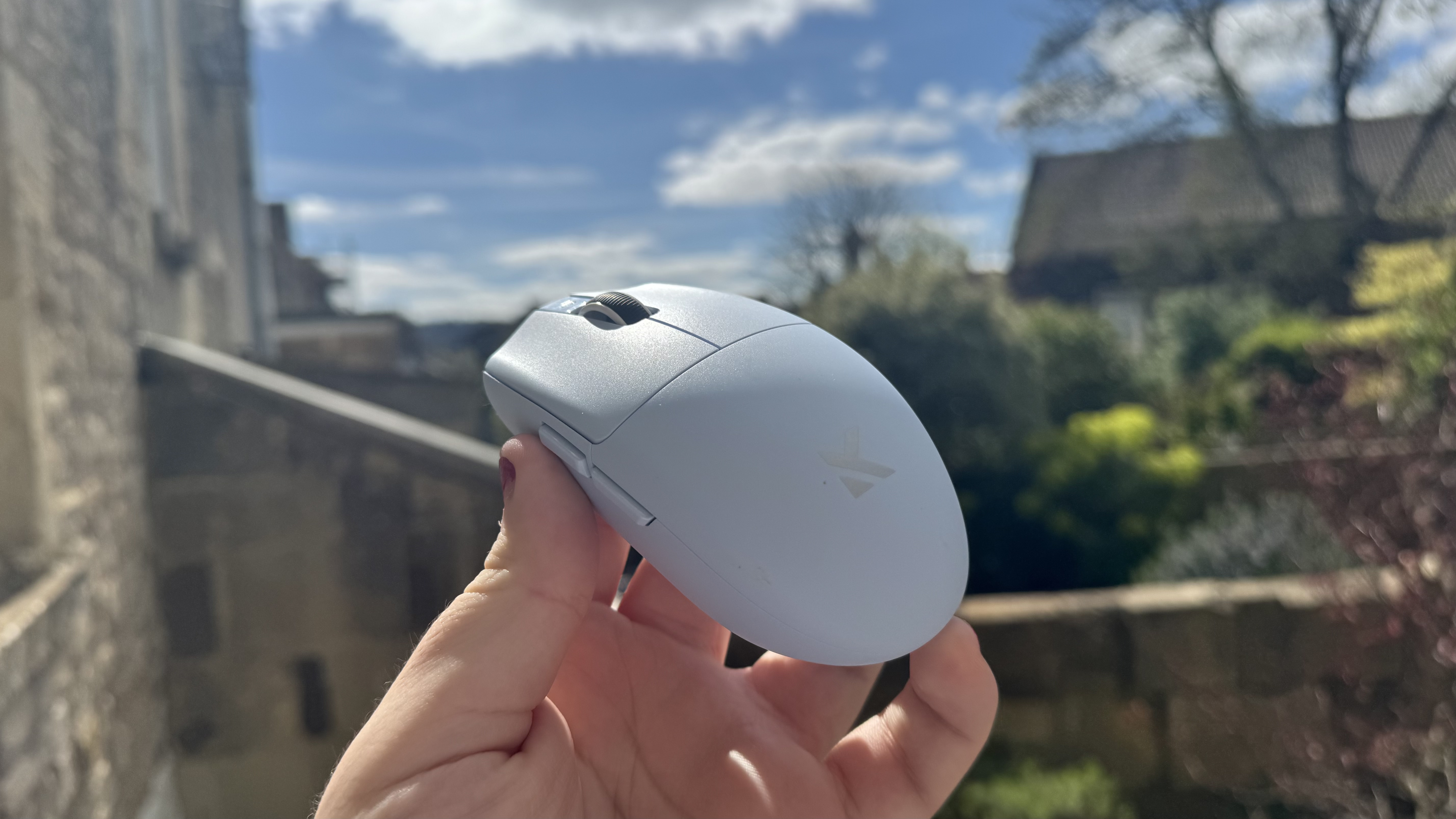 The blue Mchose G3 V2 gaming mouse held in a hand, outside