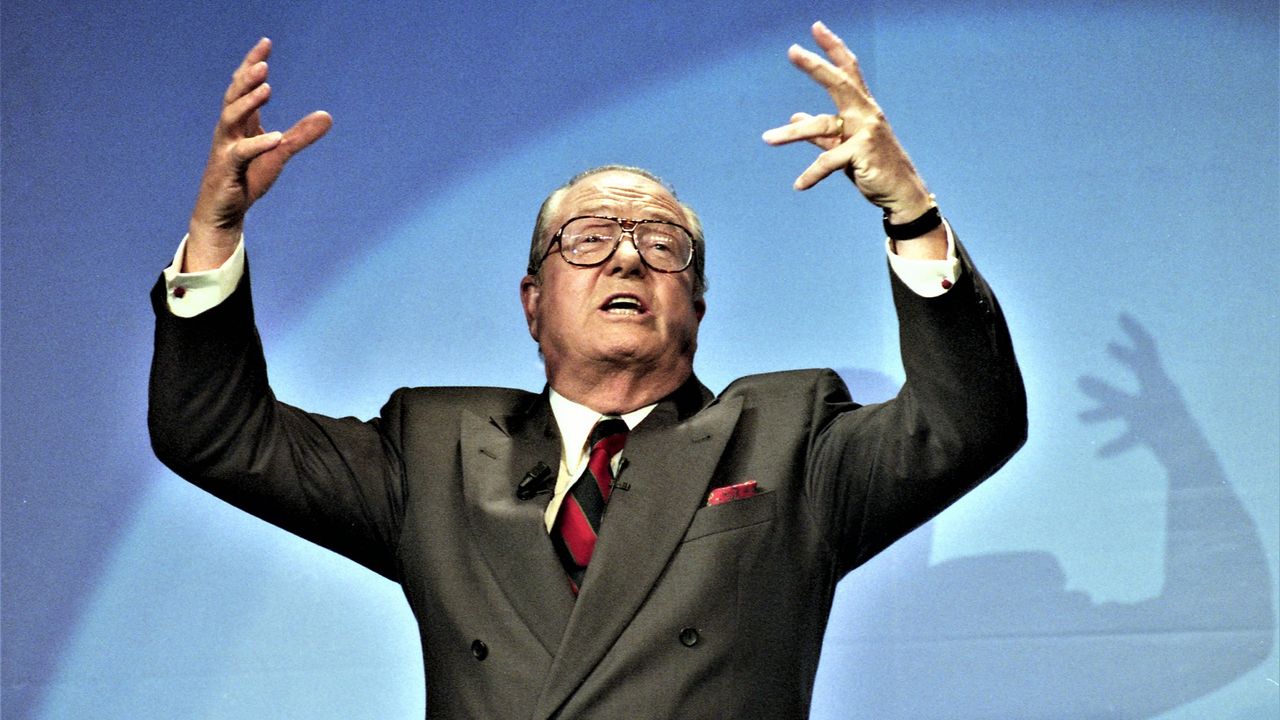 Jean-Marie Le Pen with his hands raised during a speech in 1995