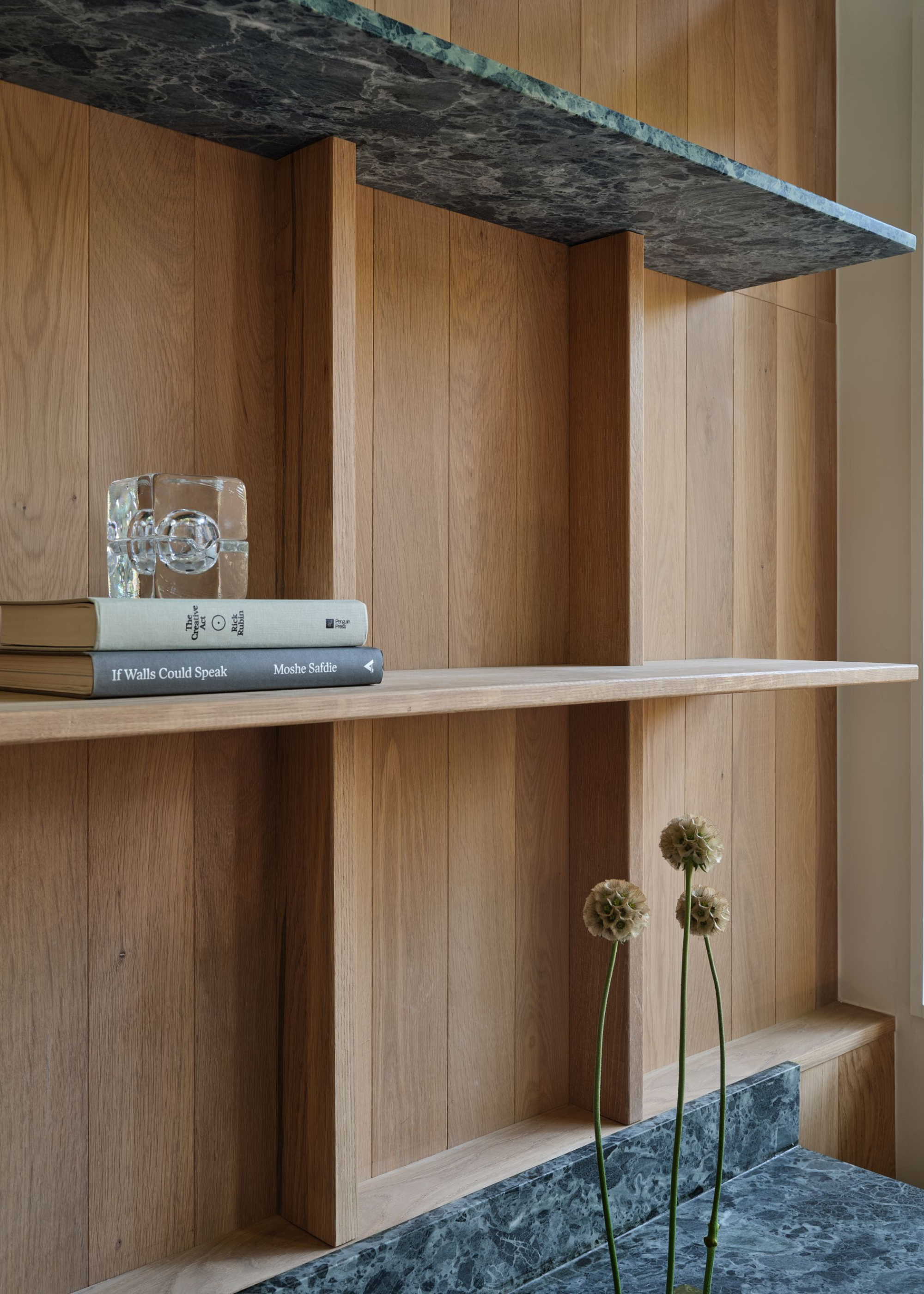 oak clad walls with green marble shelves and desk with books on the shelf