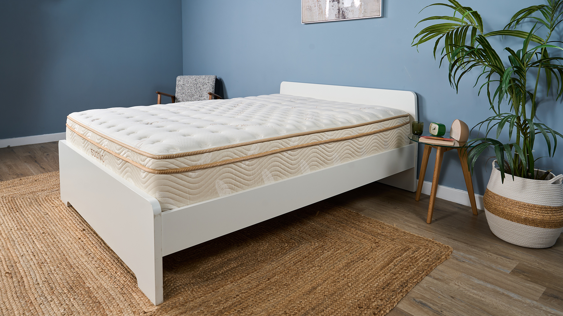 Saatva Classic Luxury Innerspring mattress on a white wooden bed frame in a blue bedroom