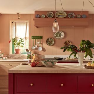 Italian inspired kitchen with pink walls and red island and slim glass pendant above island