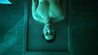 green-tinged view of a shirtless man lying on a table.