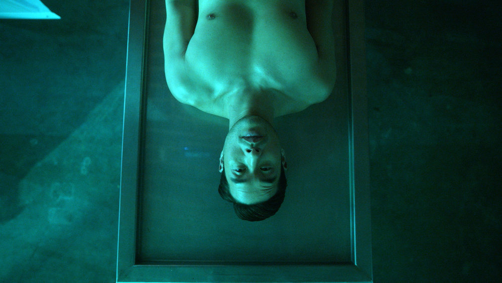 green-tinged view of a shirtless man lying on a table.