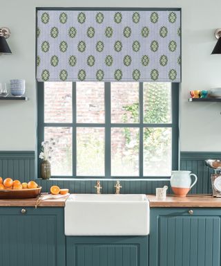 Blue motif roller blind in kitchen with wooden painted windows and wooden countertops