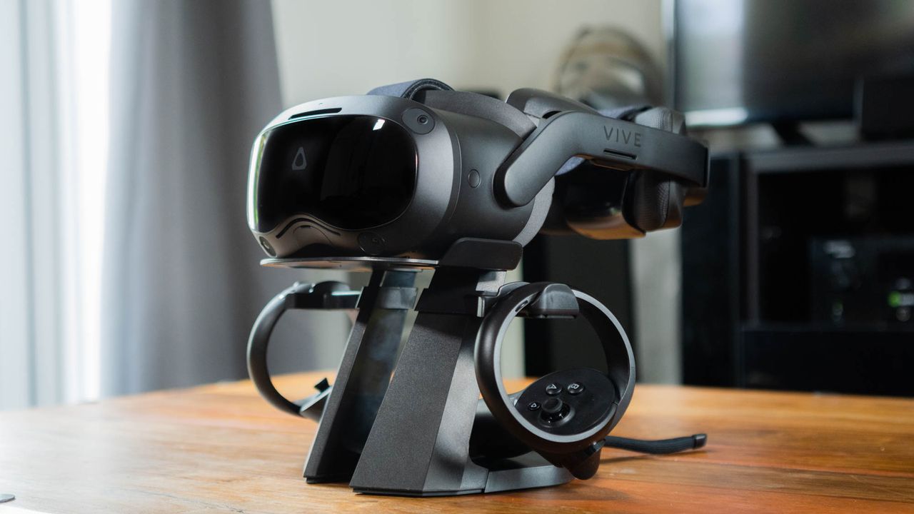 A photograph of the HTC Vive Focus 3 and its controllers, mounted on a stand on a coffee table