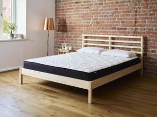 mattress on wood bed with brick walls