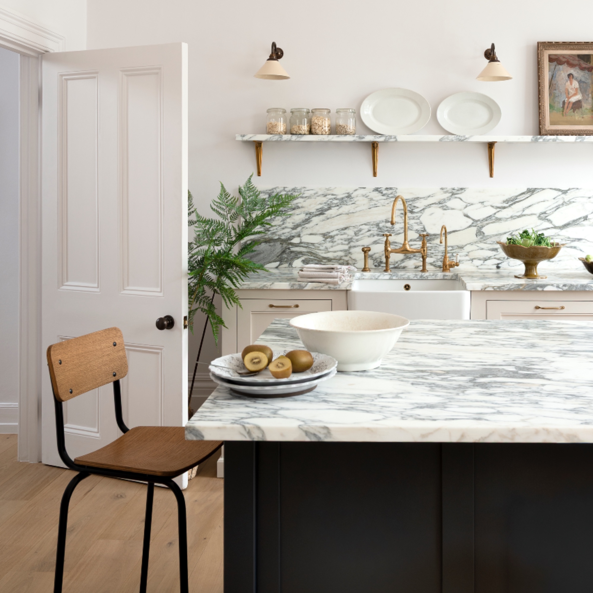 white and marble kitchen with open shelving, bar stool, butler sink, kitchen wall lights