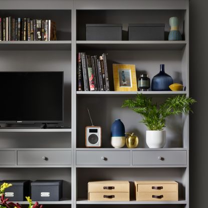 Dark grey shelving unit with TV and storage boxes in living room