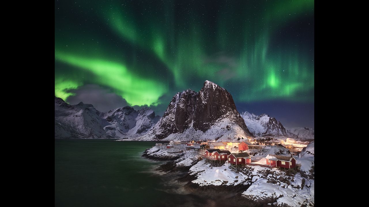 After two weeks of storm, clouds and snow in Norway's Lofoten Islands, the sky finally cleared up, providing perfect conditions for hunting the northern lights. The photographer waited patiently in their car for the light show to begin and on the first sign of the aurora borealis in the sky, he set up his camera at this famous overlook of the idyllic fishing village Hamn&oslash;y. The image is a manual exposure blend consisting of one base image for the sky and foreground plus a total of seven bracketed images to balance the highlights and shadows in the fishing village and water.