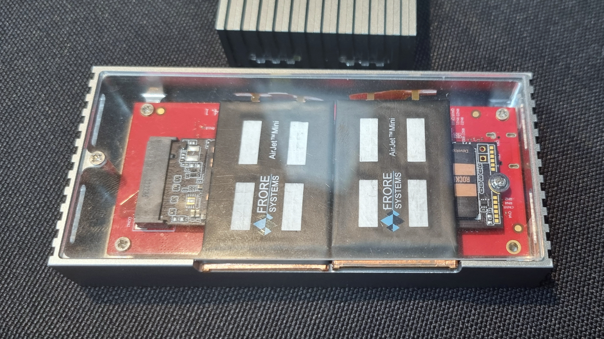 An external SSD with a perspex case panel showing the installation of two Frore AirJet Mini Slims attached to an SSD