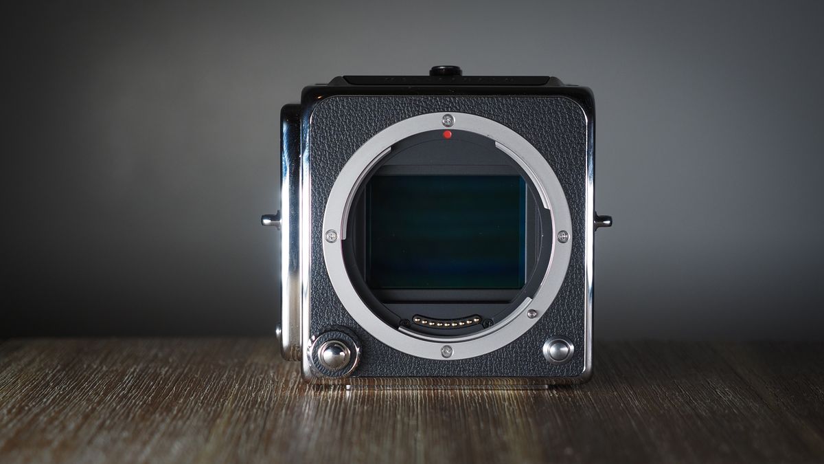 The Hasselblad 907X &amp; CFV 100C medium format camera with digital back, on a wooden table with artistic lighting