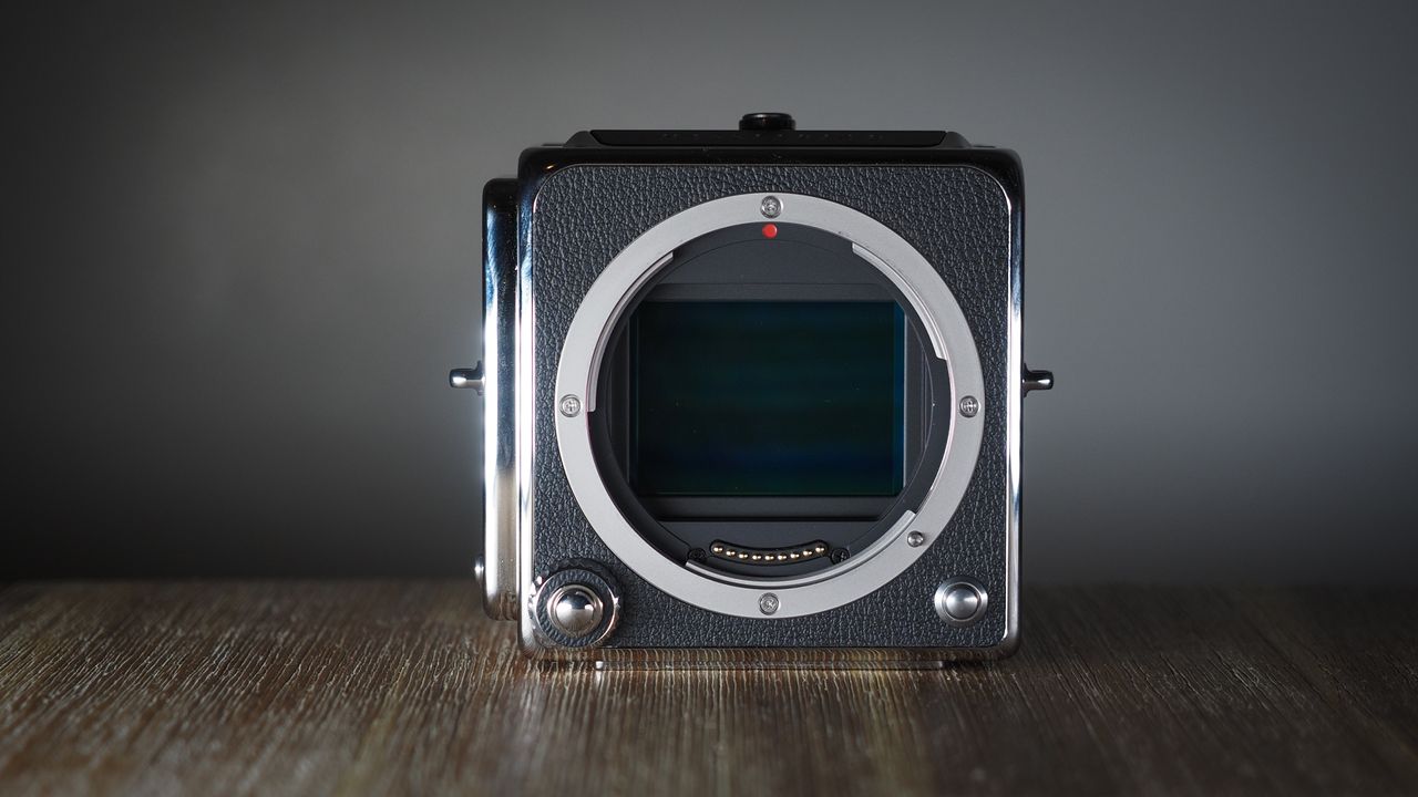 The Hasselblad 907X &amp; CFV 100C medium format camera with digital back, on a wooden table with artistic lighting