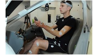 A person wearing a mocap suit while sat in a wireframe car