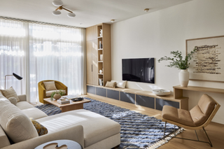 modern living room with low-slung furniture, bench seat below the mounted tv, and an armchair