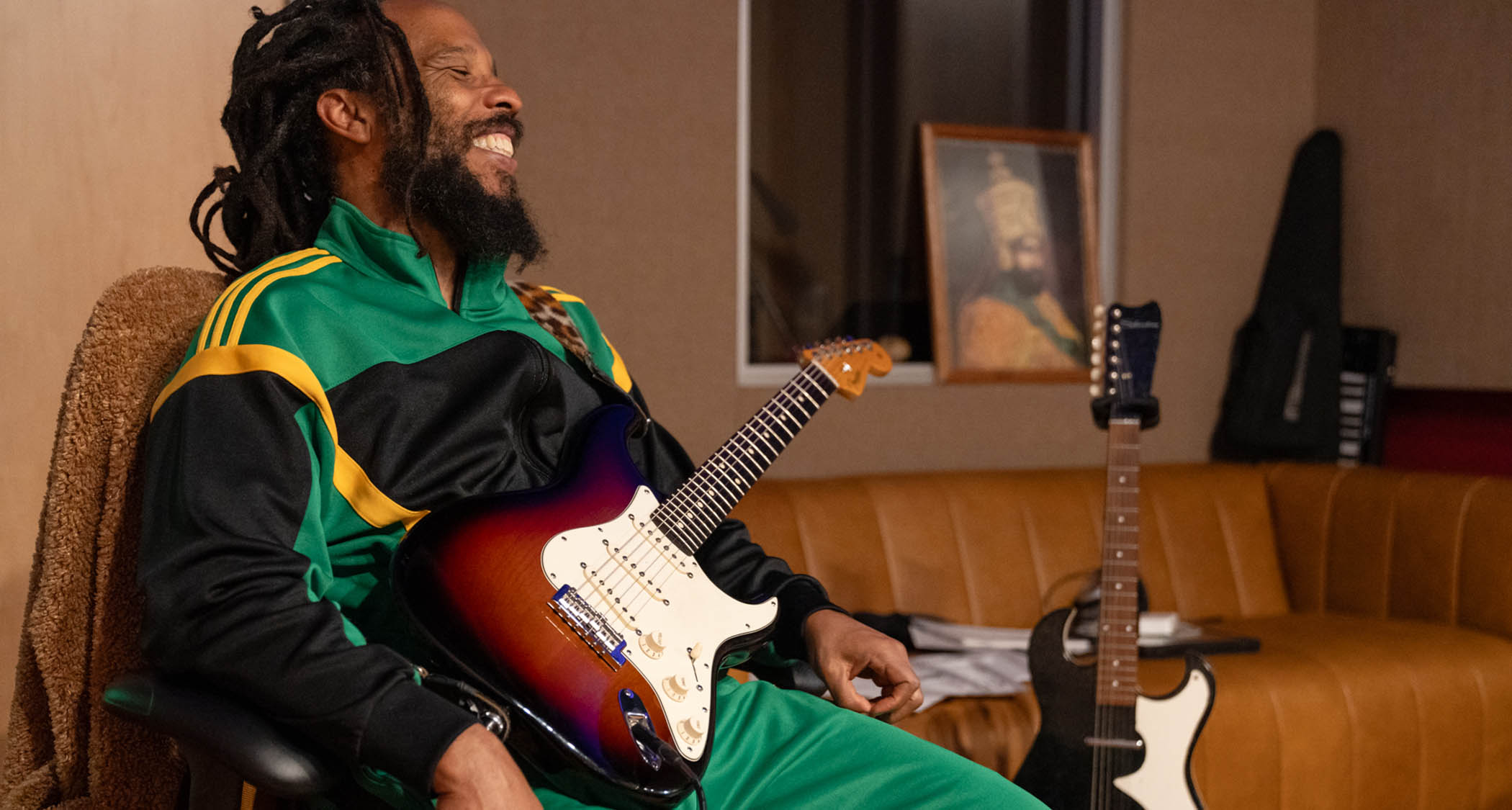 Ziggy Marley wears a Jamaican flag tracksuit and plays his Fender Stratocaster