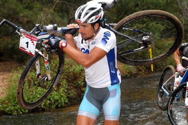 Ondrej Fotjik carries his bike across a river