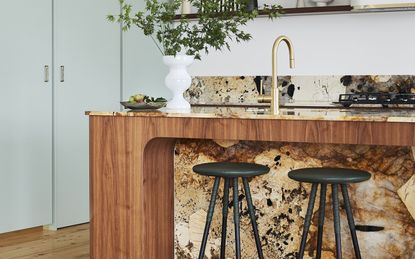 A kitchen island with marble countertop, seating and decor