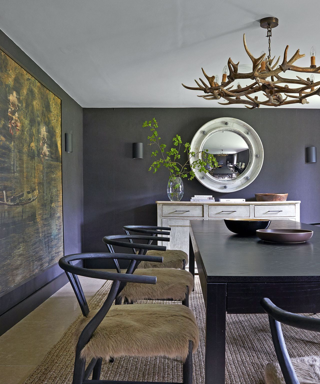 Dining room with dark gray walls, antler chandelier and black table and chairs