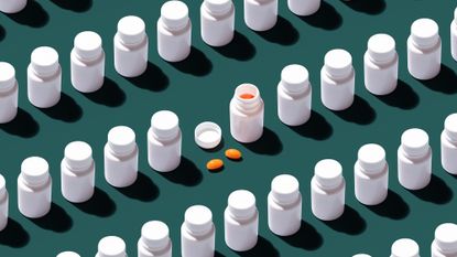 Several closed pill bottles with one open bottle with two pills