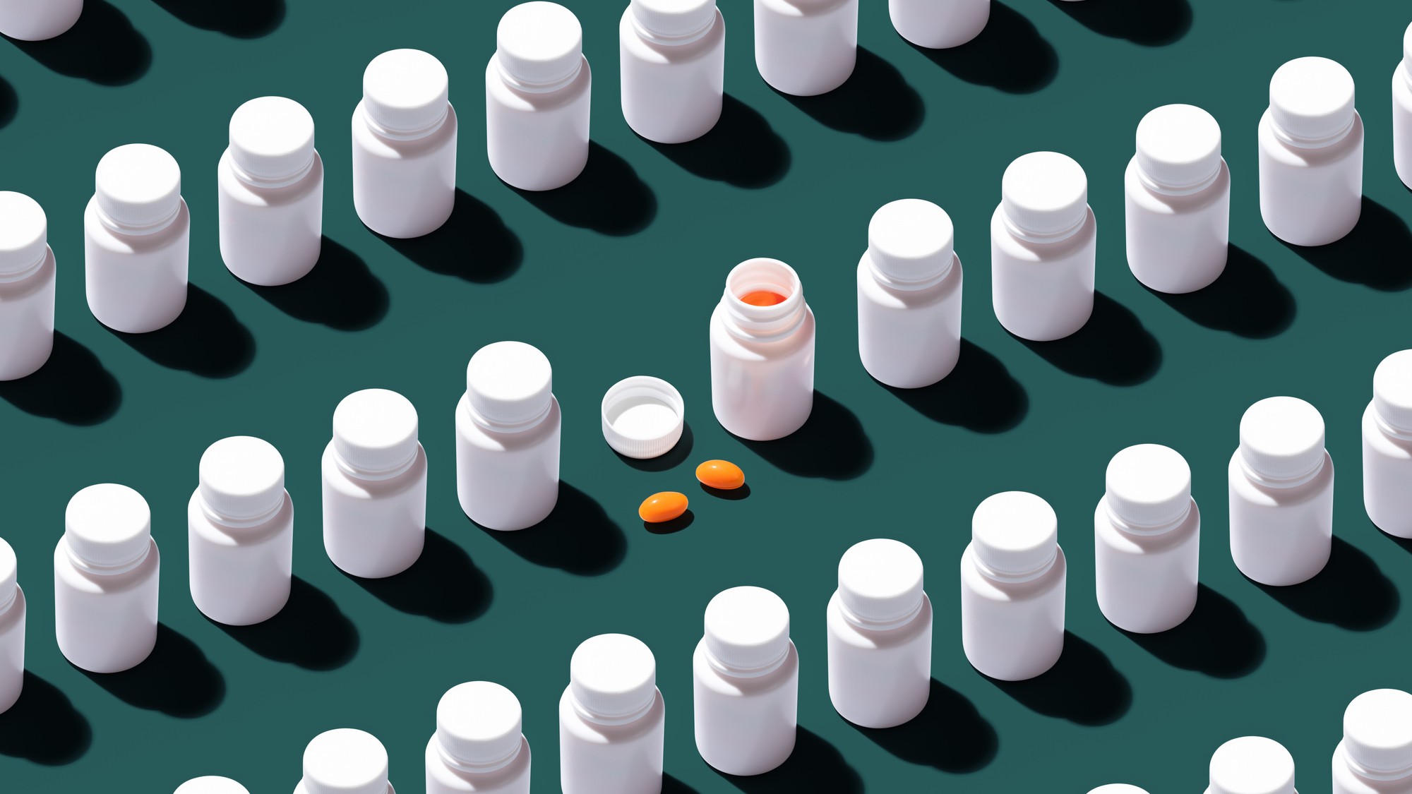 Several closed pill bottles with one open bottle with two pills