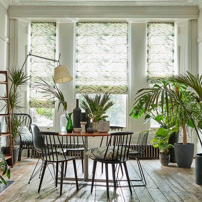 living area with wooden floor and round tables with chairs and white windows with roman blinds