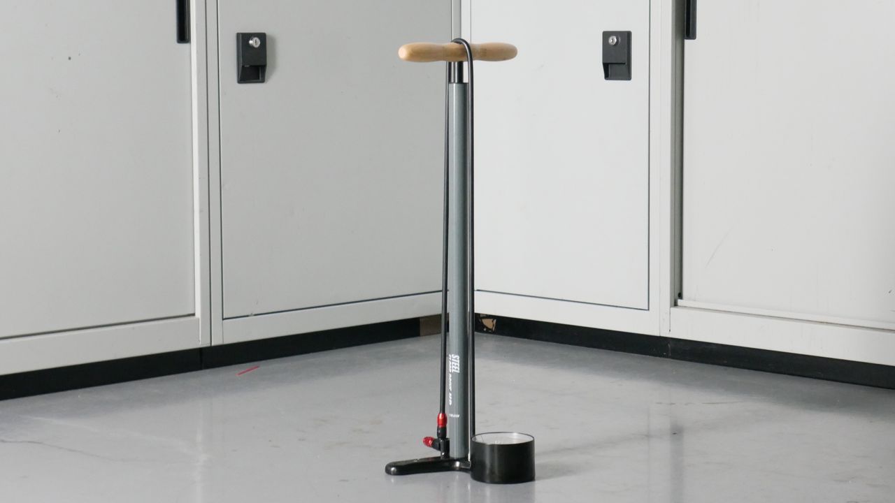 Lezyne bike track pump in Grey with a wooden handle set to a background of some workshop cabinets